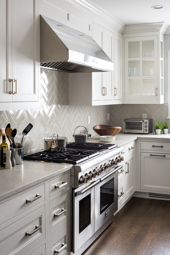 Example of a mid-sized transitional l-shaped dark wood floor open concept kitchen design in New York with an undermount sink, shaker cabinets, white cabinets, quartzite countertops, gray backsplash, ceramic backsplash, stainless steel appliances and an island
