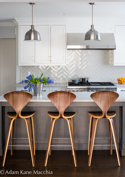 The perfect backdrop for this white kitchen is a glossy herringbone backsplash. No these are not peel and stick tiles, they are adhesive! They truly look great in this kitchen.