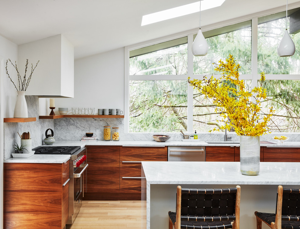 Photo of a large contemporary l-shaped kitchen/diner in New York with a single-bowl sink, flat-panel cabinets, marble worktops, white splashback, marble splashback, stainless steel appliances, light hardwood flooring, a breakfast bar, beige floors, white worktops and medium wood cabinets.