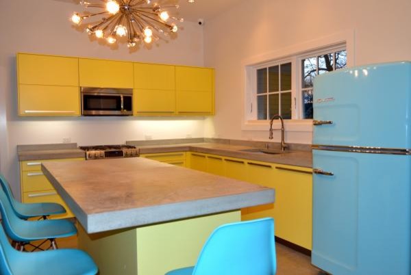 Источник вдохновения для домашнего уюта: угловая кухня среднего размера в стиле модернизм с обеденным столом, накладной мойкой, плоскими фасадами, желтыми фасадами, столешницей из акрилового камня, цветной техникой, полом из керамической плитки и островом