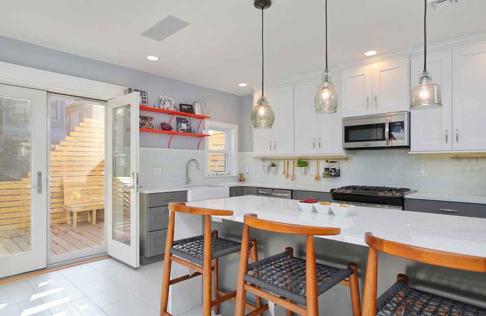 Example of a large transitional l-shaped porcelain tile kitchen design in Philadelphia with a farmhouse sink, shaker cabinets, white cabinets, quartzite countertops, glass tile backsplash, stainless steel appliances and an island