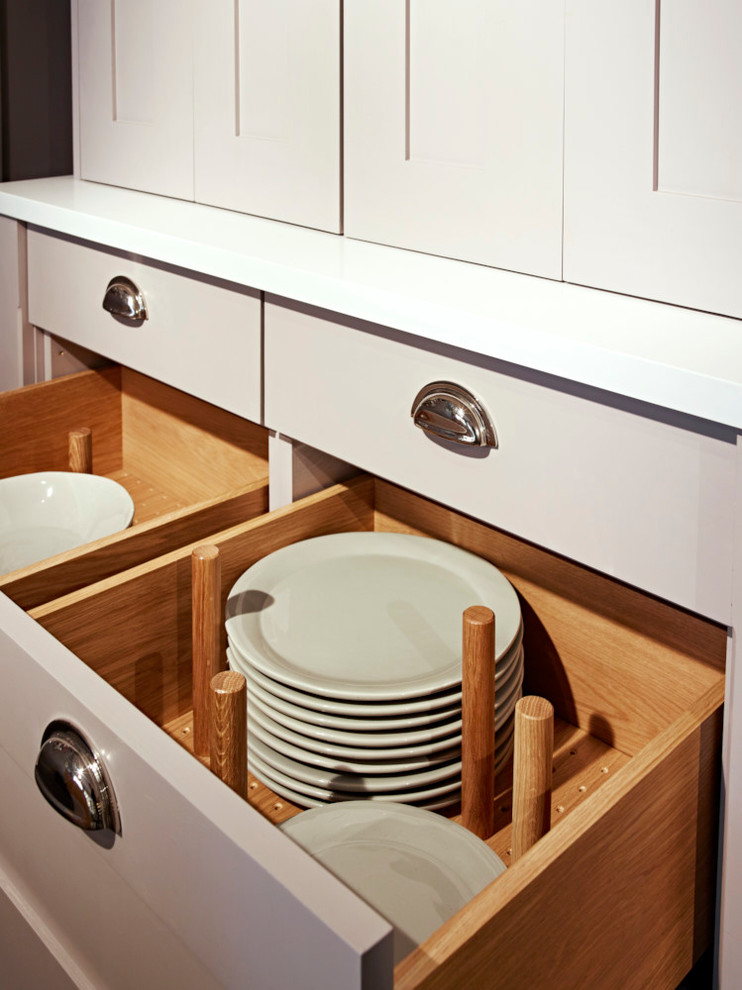Cette image montre une petite cuisine ouverte linéaire design en bois clair avec un placard avec porte à panneau encastré, un plan de travail en surface solide et îlot.