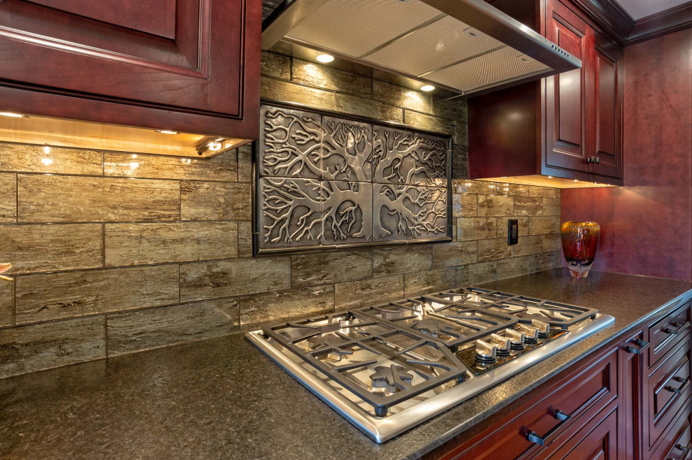 Bild på ett stort vintage brun linjärt brunt kök och matrum, med en undermonterad diskho, luckor med upphöjd panel, röda skåp, granitbänkskiva, brunt stänkskydd, stänkskydd i porslinskakel, rostfria vitvaror, ljust trägolv, en köksö och brunt golv