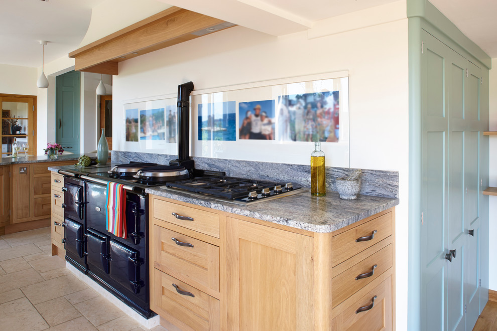 Bild på ett mycket stort lantligt kök och matrum, med en undermonterad diskho, skåp i shakerstil, skåp i mellenmörkt trä, granitbänkskiva, glaspanel som stänkskydd, svarta vitvaror, kalkstensgolv och en köksö