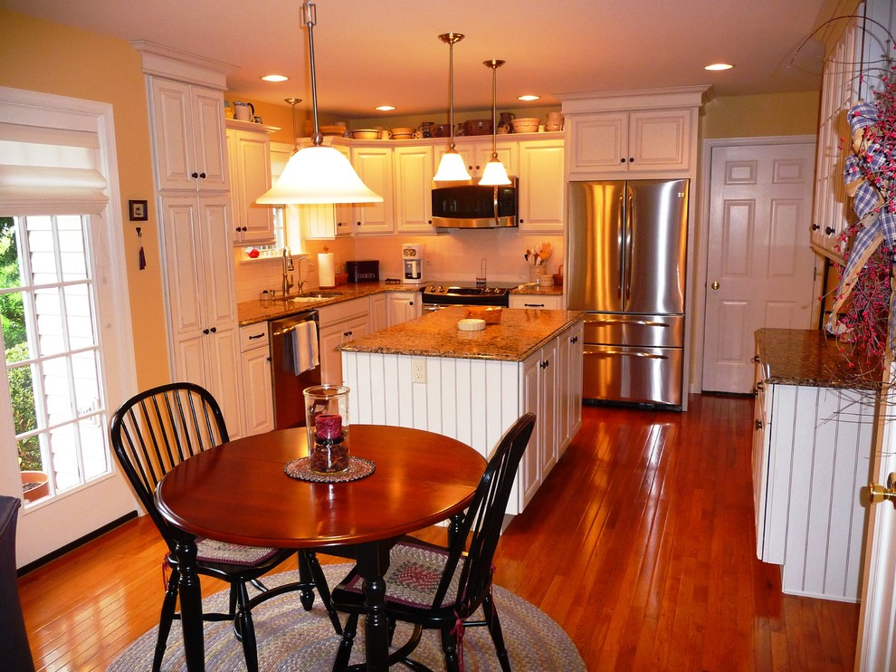 Bild på ett mellanstort vintage kök, med en undermonterad diskho, luckor med upphöjd panel, vita skåp, bänkskiva i kvarts, stänkskydd i keramik, rostfria vitvaror, vitt stänkskydd, mellanmörkt trägolv, en köksö och brunt golv
