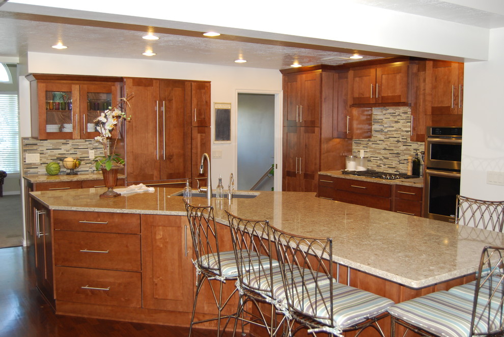 Bild på ett stort orientaliskt kök, med en undermonterad diskho, luckor med infälld panel, skåp i mellenmörkt trä, flerfärgad stänkskydd, stänkskydd i mosaik, en köksö, bänkskiva i kvarts, integrerade vitvaror, mörkt trägolv och brunt golv