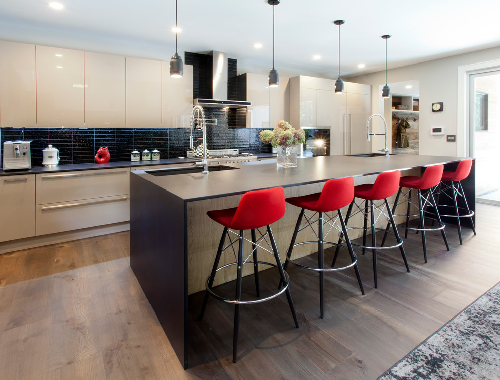 Inspiration for a modern l-shaped medium tone wood floor open concept kitchen remodel in New York with an undermount sink, flat-panel cabinets, white cabinets, black backsplash, ceramic backsplash and an island