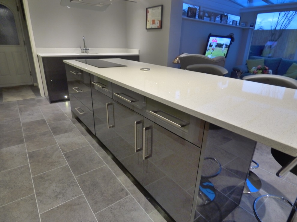 This is an example of a large contemporary galley open plan kitchen in Other with flat-panel cabinets, grey cabinets, granite worktops, integrated appliances and an island.