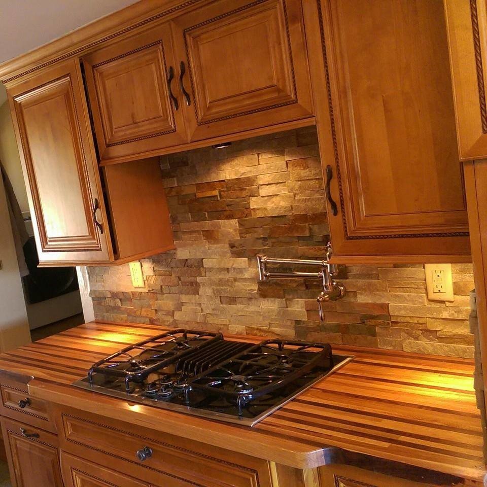 Rustik inredning av ett stort kök, med luckor med upphöjd panel, skåp i mellenmörkt trä, träbänkskiva, grått stänkskydd, stänkskydd i stenkakel och rostfria vitvaror