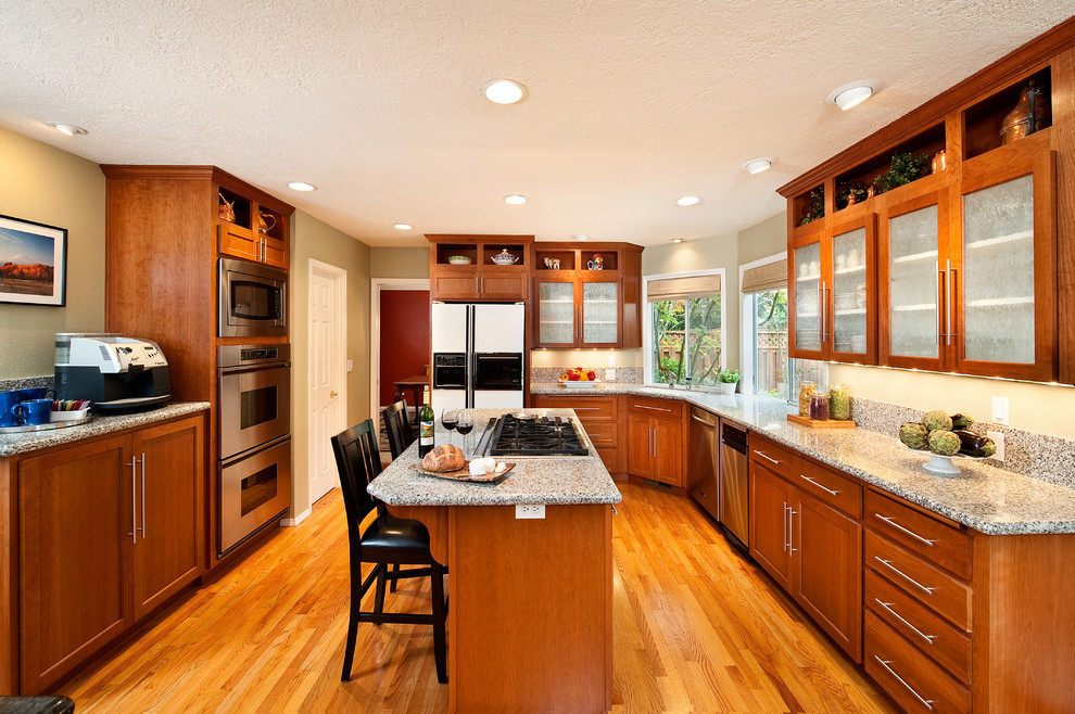 Eat-in kitchen - mid-sized traditional medium tone wood floor eat-in kitchen idea in Portland with recessed-panel cabinets, medium tone wood cabinets, marble countertops, stainless steel appliances, an island and an undermount sink