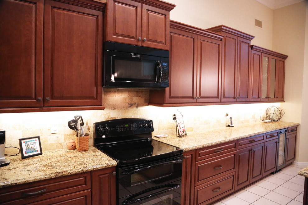 Eat-in kitchen - large traditional l-shaped eat-in kitchen idea in Orlando with raised-panel cabinets, dark wood cabinets, granite countertops, black appliances and an island