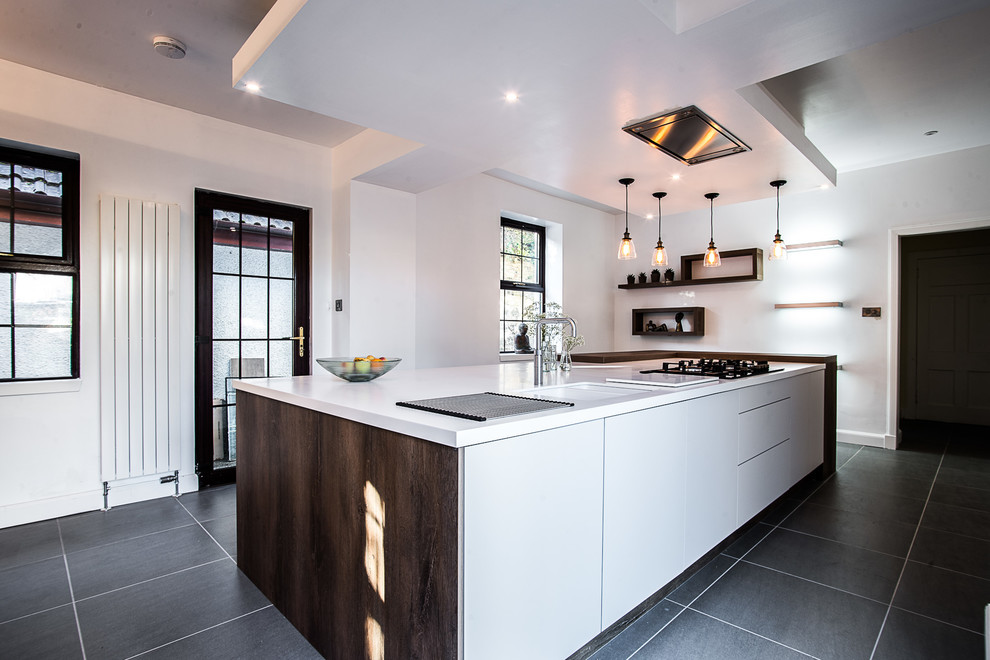 This is an example of a large modern single-wall enclosed kitchen in Glasgow with an integrated sink, flat-panel cabinets, white cabinets, composite countertops, metallic splashback, mirror splashback, stainless steel appliances, ceramic flooring, an island and grey floors.