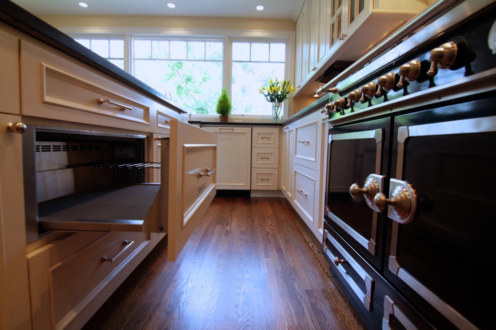 Foto de cocina actual con puertas de armario blancas y suelo de madera oscura