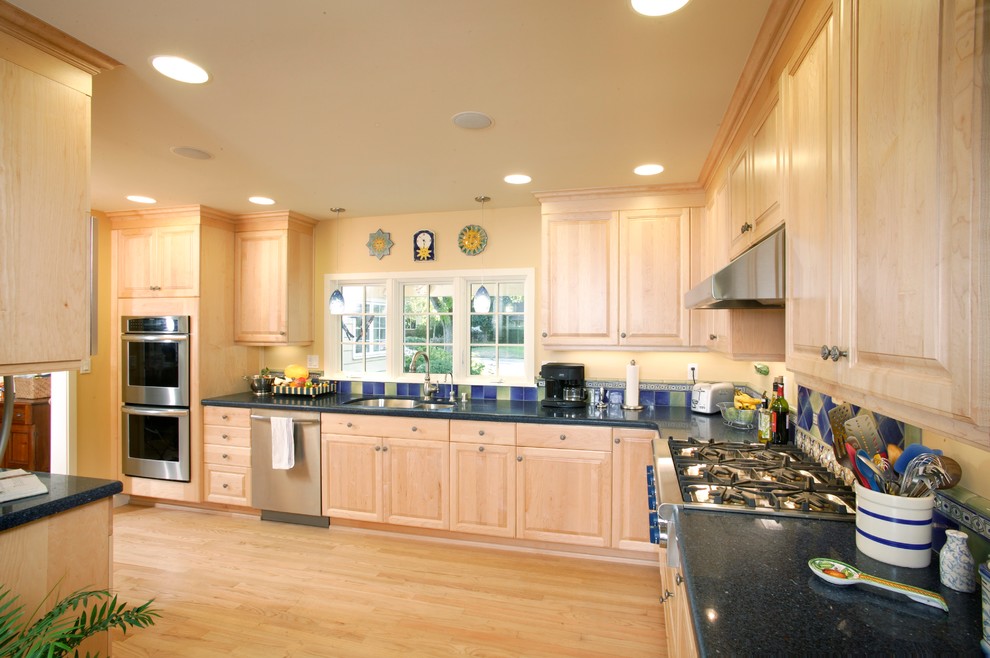 Example of a large classic u-shaped light wood floor enclosed kitchen design in Sacramento with a double-bowl sink, light wood cabinets, granite countertops, blue backsplash, stainless steel appliances, no island, raised-panel cabinets and ceramic backsplash