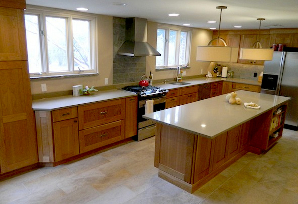 This is an example of a modern l-shaped kitchen/diner in Philadelphia with a submerged sink, recessed-panel cabinets, medium wood cabinets, granite worktops, beige splashback, stone slab splashback, stainless steel appliances, ceramic flooring and an island.