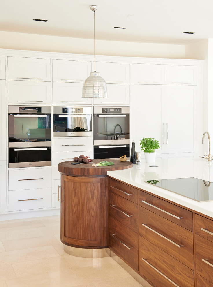 Ejemplo de cocina actual con armarios estilo shaker, puertas de armario blancas, electrodomésticos de acero inoxidable y una isla