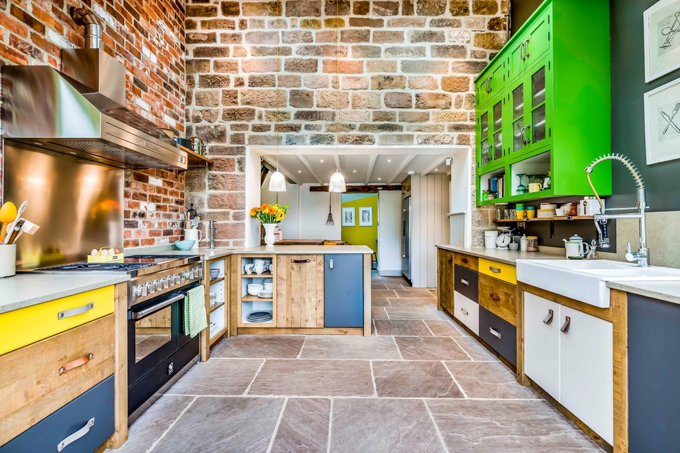 This is an example of a medium sized bohemian u-shaped kitchen in West Midlands with a belfast sink, green cabinets, black appliances, a breakfast bar, flat-panel cabinets and grey floors.