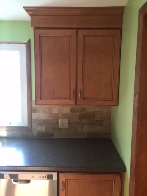 Modelo de cocinas en L clásica de tamaño medio cerrada con fregadero bajoencimera, armarios con paneles empotrados, puertas de armario de madera clara, encimera de acrílico, salpicadero marrón, salpicadero de azulejos de cerámica, electrodomésticos de acero inoxidable, suelo de baldosas de cerámica, una isla y suelo beige