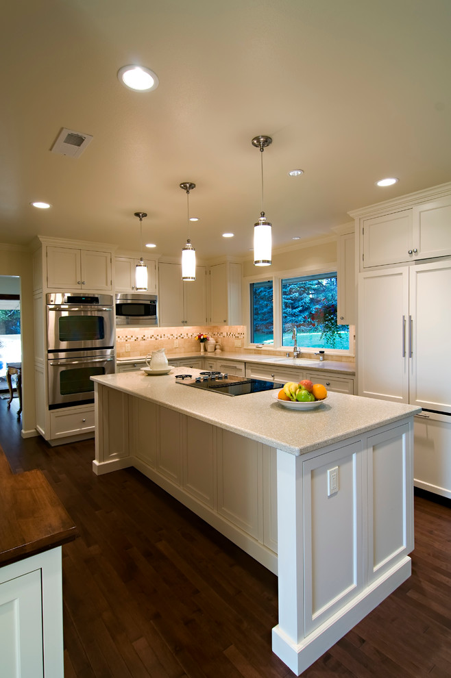 Example of a mid-sized classic u-shaped medium tone wood floor and beige floor open concept kitchen design in Seattle with shaker cabinets, white cabinets, quartz countertops, paneled appliances and an island