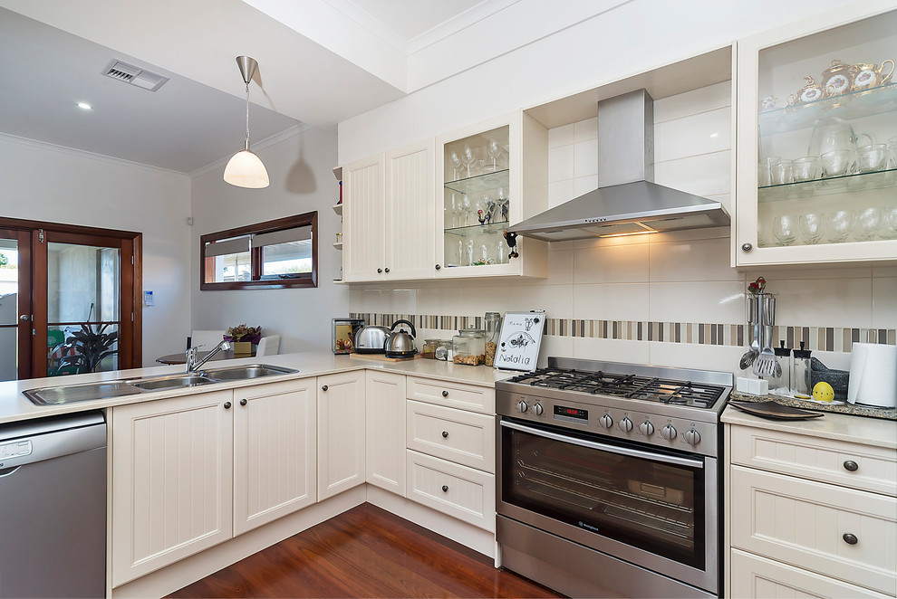 Photo of a medium sized contemporary u-shaped open plan kitchen in Adelaide with a double-bowl sink, beaded cabinets, beige cabinets, granite worktops, beige splashback, ceramic splashback, stainless steel appliances and a breakfast bar.