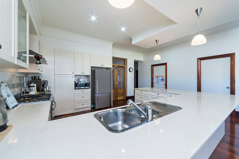 Exempel på ett mellanstort modernt kök, med luckor med profilerade fronter, beige skåp, granitbänkskiva, beige stänkskydd, stänkskydd i keramik, rostfria vitvaror och en halv köksö