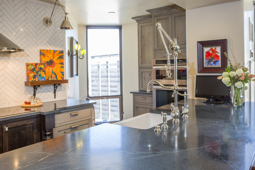 Inspiration for a small eclectic galley vinyl floor open concept kitchen remodel in Denver with a farmhouse sink, recessed-panel cabinets, gray cabinets, soapstone countertops, white backsplash, ceramic backsplash, stainless steel appliances and a peninsula