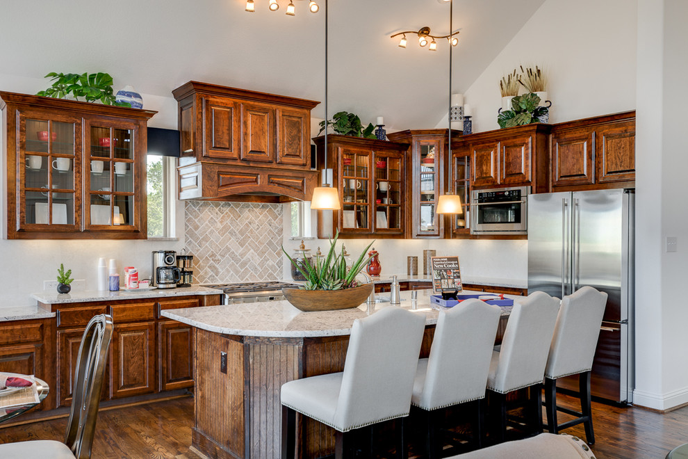 Exemple d'une cuisine ouverte chic en L et bois brun avec un plan de travail en granite, une crédence beige, une crédence en carrelage de pierre, un électroménager en acier inoxydable, un sol en bois brun et îlot.