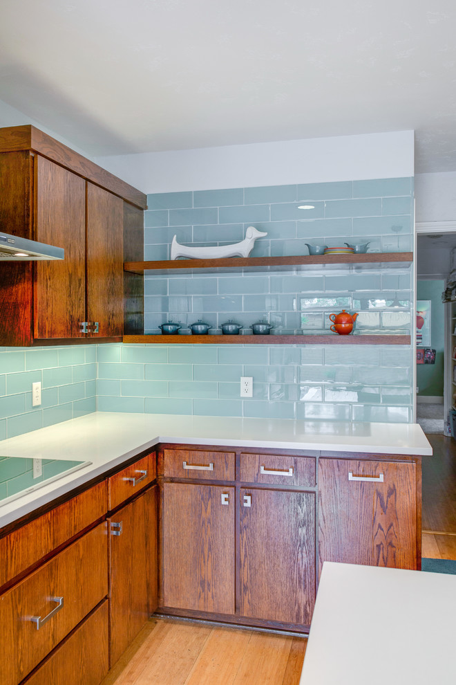 Idéer för att renovera ett mellanstort 60 tals vit vitt kök, med en undermonterad diskho, släta luckor, skåp i mellenmörkt trä, bänkskiva i kvarts, blått stänkskydd, stänkskydd i glaskakel, rostfria vitvaror och en halv köksö