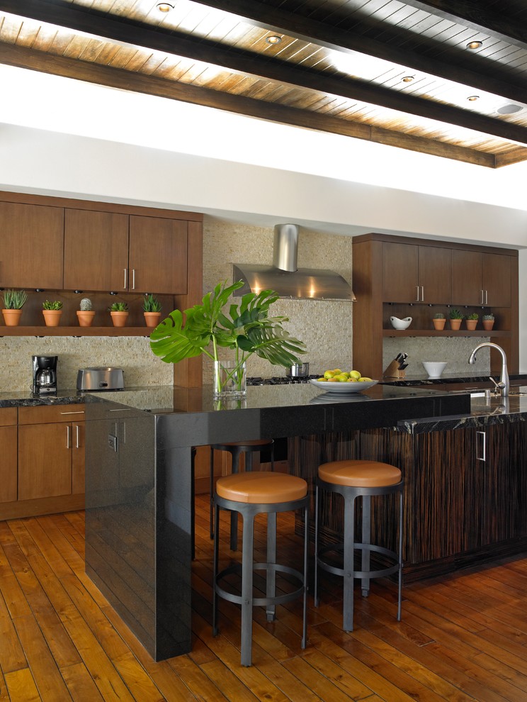 На фото: параллельная кухня в современном стиле с плоскими фасадами, темными деревянными фасадами, бежевым фартуком, фартуком из плитки мозаики, паркетным полом среднего тона и островом с