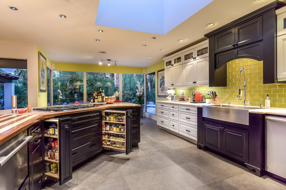 Example of a large 1950s l-shaped porcelain tile and gray floor eat-in kitchen design in Las Vegas with a farmhouse sink, raised-panel cabinets, white cabinets, marble countertops, green backsplash, glass tile backsplash, stainless steel appliances and an island