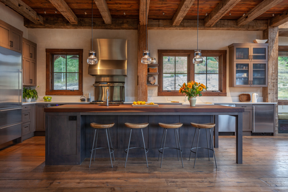 Design ideas for a medium sized rustic l-shaped open plan kitchen in Denver with shaker cabinets, dark wood cabinets, stainless steel appliances, dark hardwood flooring, an island, brown floors and white worktops.