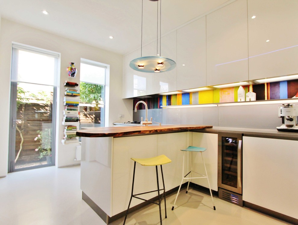 This is an example of a small contemporary l-shaped enclosed kitchen in London with an integrated sink, glass-front cabinets, grey cabinets, quartz worktops, grey splashback, glass sheet splashback, stainless steel appliances and a breakfast bar.