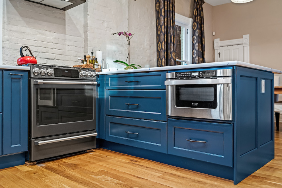 Foto på ett mellanstort eklektiskt vit kök, med en rustik diskho, luckor med infälld panel, blå skåp, bänkskiva i kvarts, grått stänkskydd, stänkskydd i tegel, färgglada vitvaror, mellanmörkt trägolv, en halv köksö och brunt golv