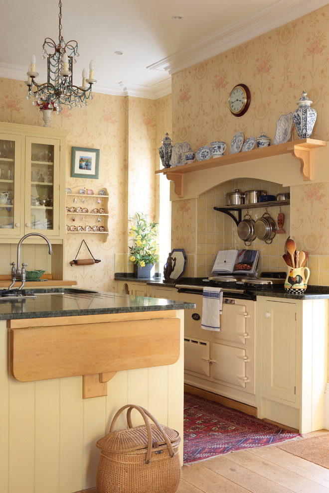 Klassisk inredning av ett l-kök, med en undermonterad diskho, luckor med infälld panel, gula skåp, gult stänkskydd, färgglada vitvaror, mellanmörkt trägolv, en köksö och brunt golv