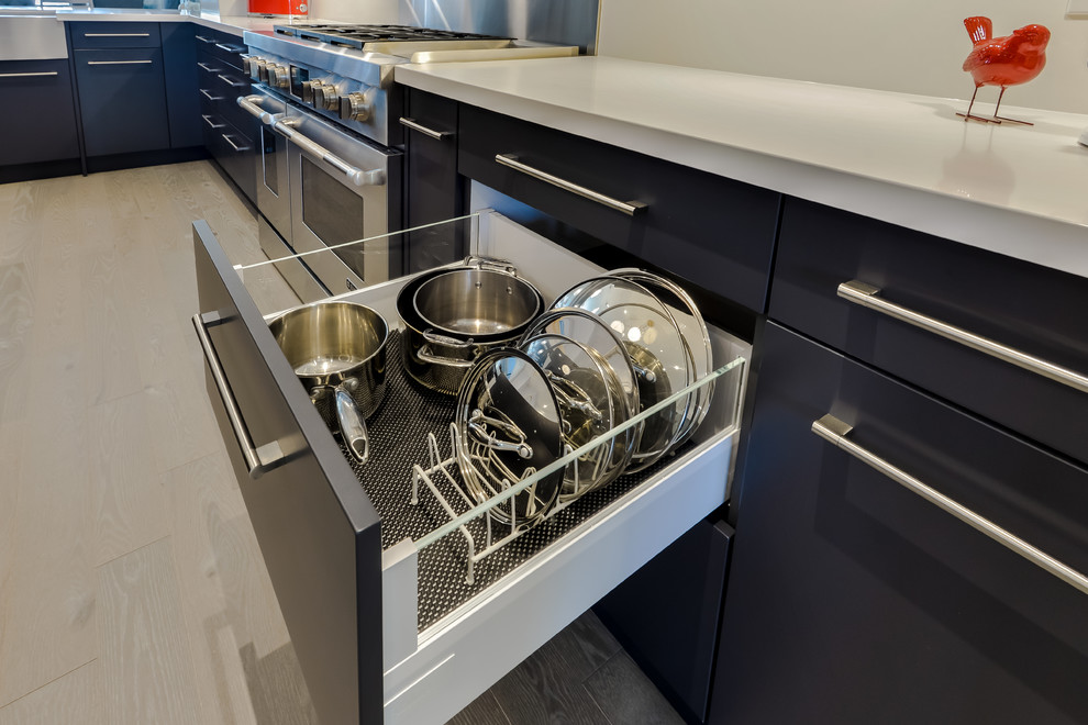 Medium sized contemporary l-shaped kitchen/diner in Toronto with a belfast sink, flat-panel cabinets, grey cabinets, stainless steel worktops, white splashback, stone slab splashback, stainless steel appliances and an island.