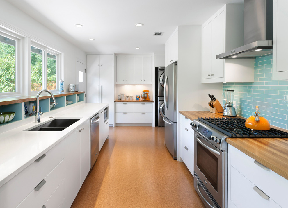 Example of a trendy kitchen design in Austin with an undermount sink, flat-panel cabinets, white cabinets, blue backsplash, stainless steel appliances and no island