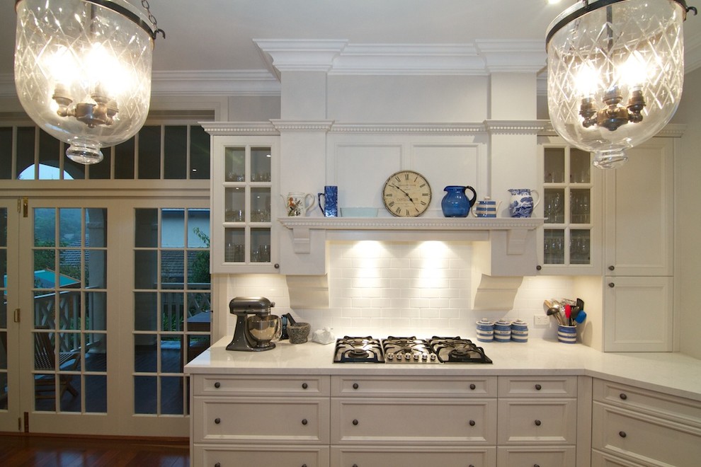 Exempel på ett stort lantligt kök, med en rustik diskho, luckor med infälld panel, vita skåp, bänkskiva i kvarts, vitt stänkskydd, stänkskydd i porslinskakel, rostfria vitvaror, mörkt trägolv och en köksö