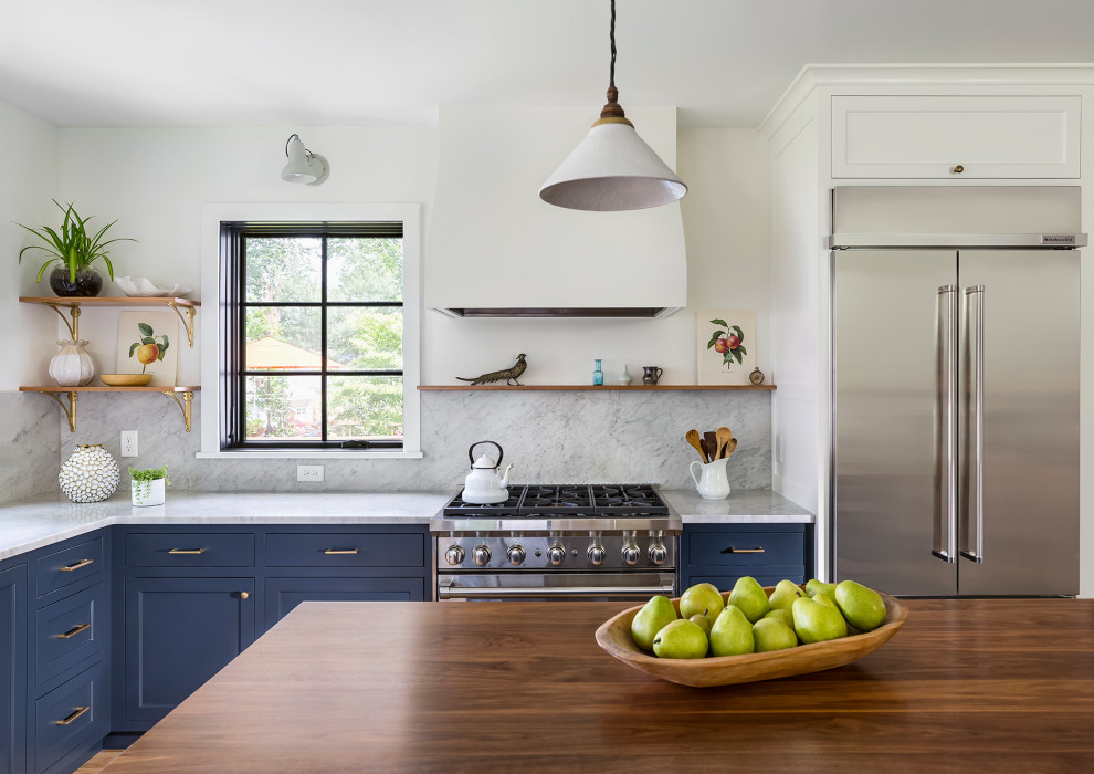 Foto på ett avskilt, mellanstort lantligt brun l-kök, med en undermonterad diskho, luckor med infälld panel, blå skåp, träbänkskiva, vitt stänkskydd, stänkskydd i marmor, rostfria vitvaror, mellanmörkt trägolv, en köksö och vitt golv