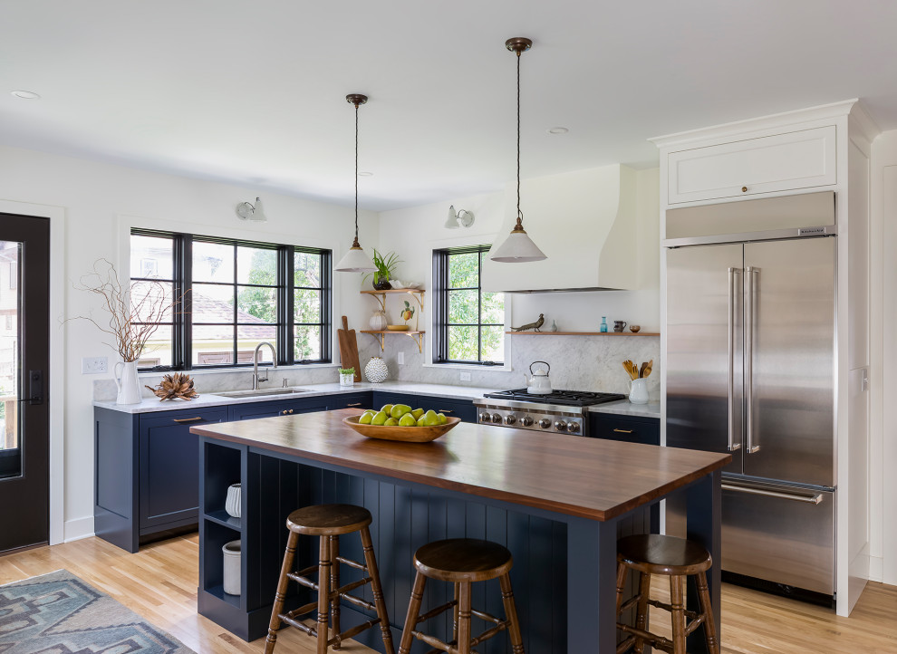 Exempel på ett avskilt, mellanstort lantligt brun brunt l-kök, med en undermonterad diskho, luckor med infälld panel, blå skåp, träbänkskiva, vitt stänkskydd, stänkskydd i marmor, rostfria vitvaror, mellanmörkt trägolv, en köksö och vitt golv