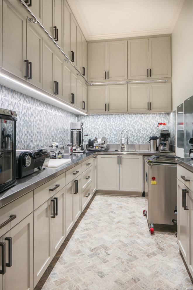 Photo of a large traditional l-shaped enclosed kitchen in New Orleans with an integrated sink, shaker cabinets, white cabinets, stainless steel worktops, grey splashback, glass tiled splashback, stainless steel appliances, beige floors and grey worktops.
