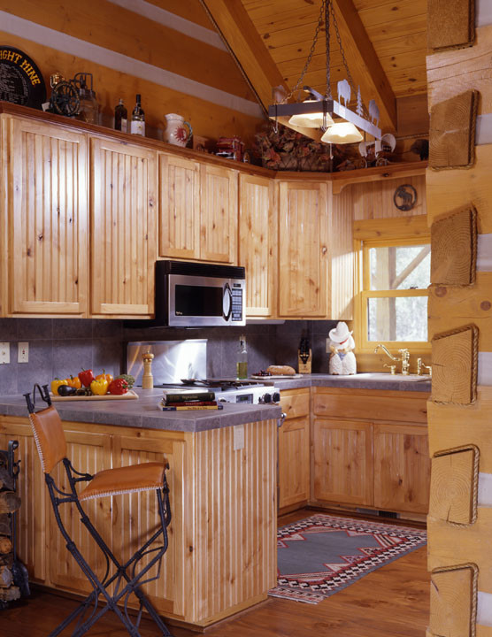 Cette image montre une petite cuisine ouverte chalet en bois clair avec un évier posé, un placard à porte affleurante, plan de travail carrelé, une crédence grise, une crédence en céramique, un électroménager en acier inoxydable et un sol en bois brun.
