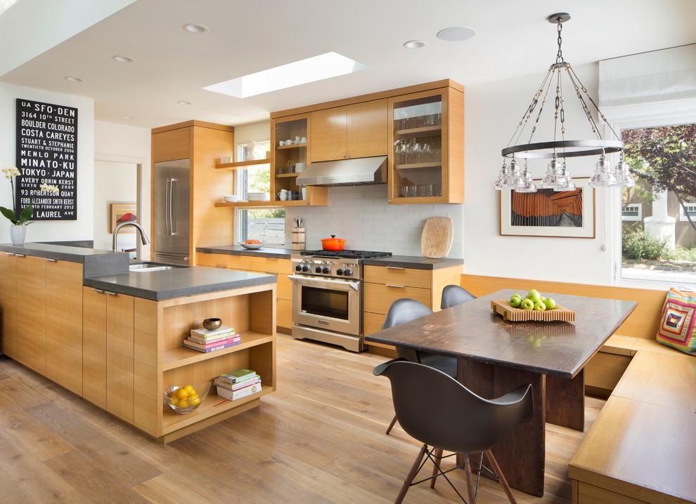 Inspiration for a mid-sized modern galley light wood floor eat-in kitchen remodel in San Francisco with an undermount sink, flat-panel cabinets, light wood cabinets, solid surface countertops, white backsplash, glass tile backsplash, stainless steel appliances and a peninsula