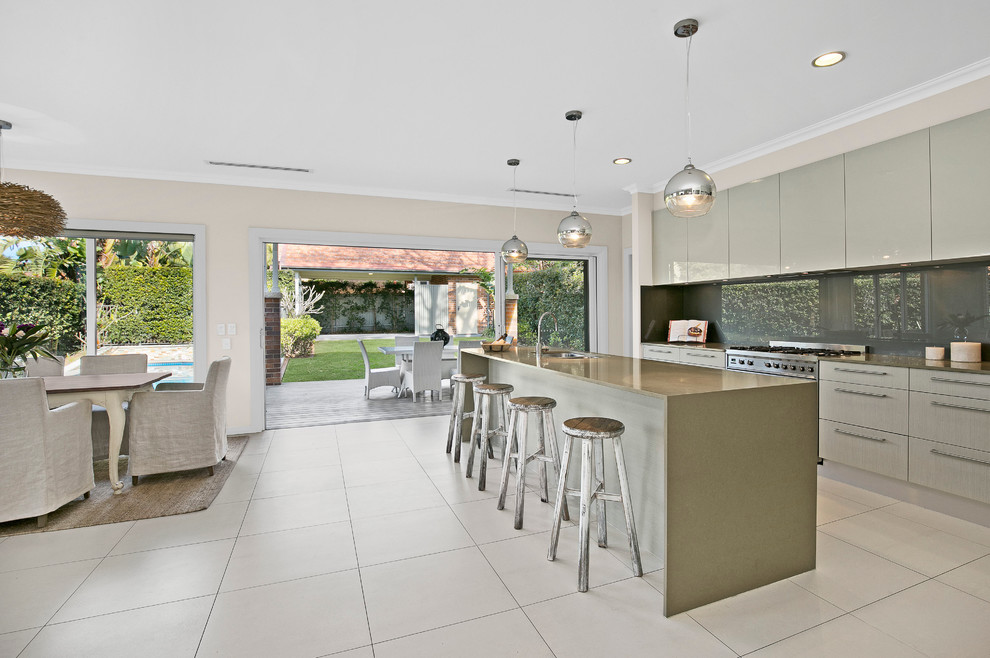 This is an example of a medium sized contemporary galley open plan kitchen in Sydney with a double-bowl sink, grey splashback, glass sheet splashback, stainless steel appliances and an island.