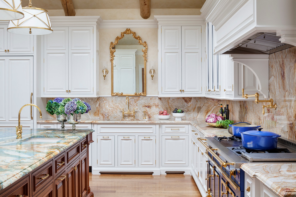 Inredning av ett klassiskt stort u-kök, med marmorbänkskiva, rosa stänkskydd, ljust trägolv, en köksö, en enkel diskho, luckor med upphöjd panel, vita skåp, stänkskydd i sten och integrerade vitvaror