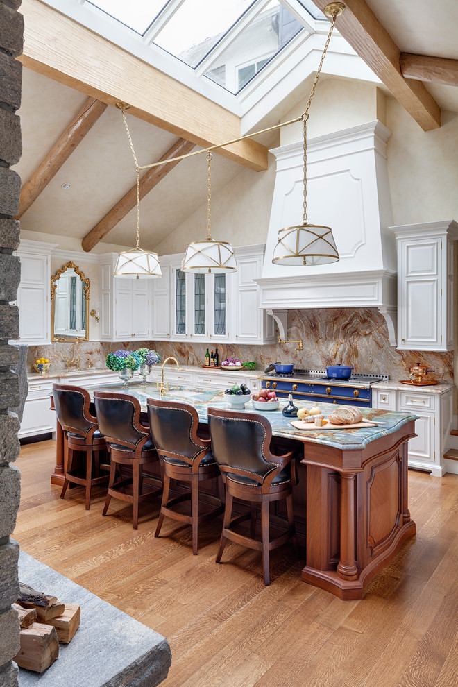 Bild på ett stort vintage u-kök, med marmorbänkskiva, rosa stänkskydd, ljust trägolv, en köksö, en enkel diskho, luckor med upphöjd panel, vita skåp, stänkskydd i sten och integrerade vitvaror