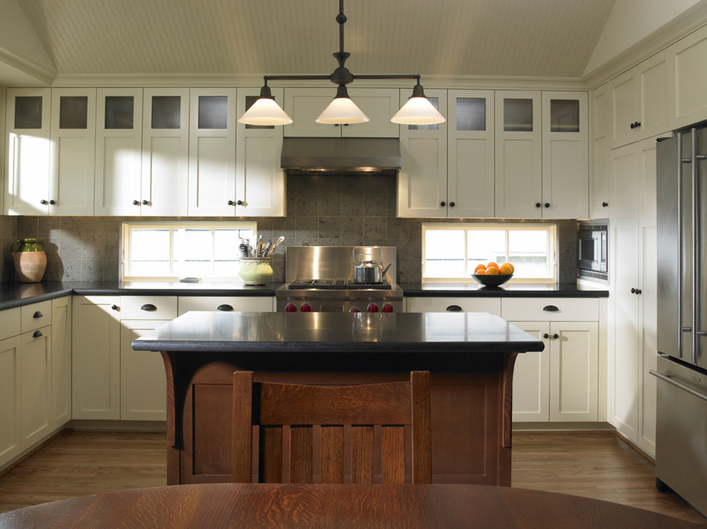 シアトルにあるトラディショナルスタイルのおしゃれなL型キッチン (シルバーの調理設備、御影石カウンター、ライムストーンのキッチンパネル、グレーとクリーム色) の写真