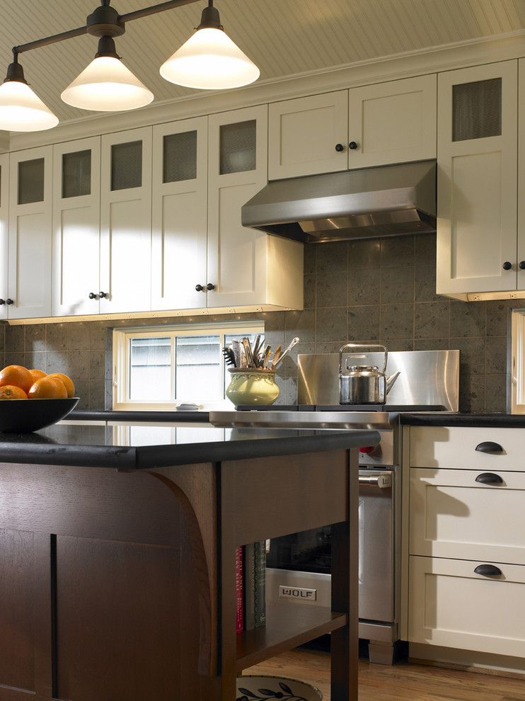 На фото: кухня в классическом стиле с техникой из нержавеющей стали, фасадами в стиле шейкер и серым фартуком