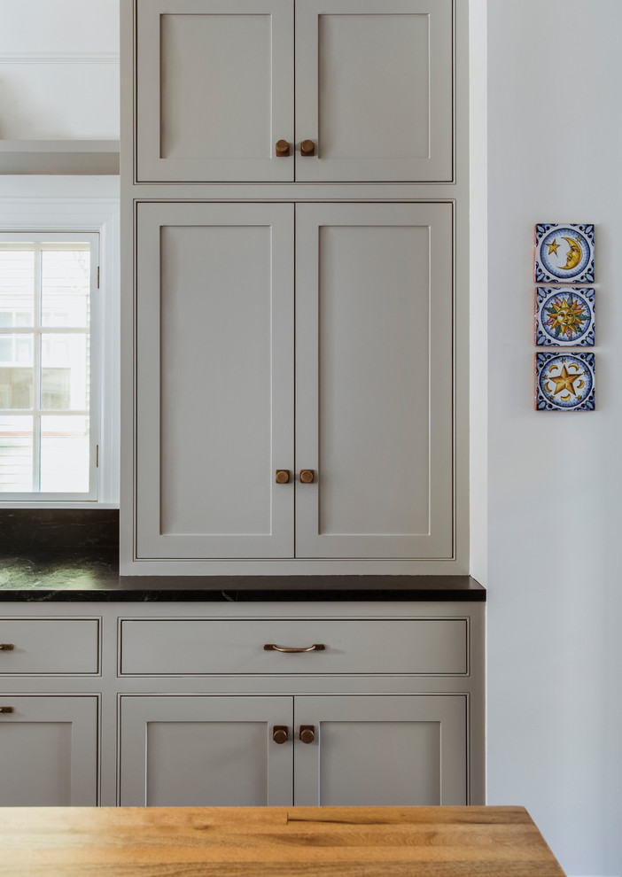 Aménagement d'une grande arrière-cuisine encastrable classique en U avec un évier encastré, un placard à porte affleurante, des portes de placard grises, une crédence bleue, îlot, un sol gris et plan de travail noir.