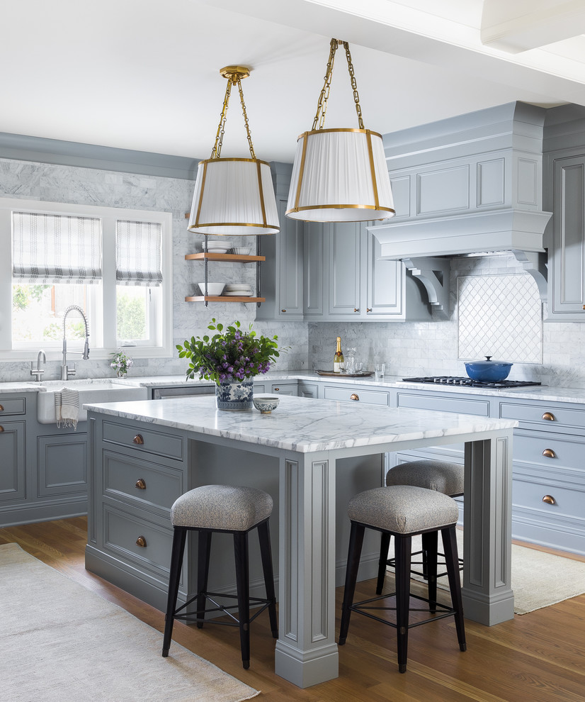 This is an example of a classic l-shaped kitchen in Seattle with an island, a belfast sink, recessed-panel cabinets, grey cabinets, grey splashback, light hardwood flooring and grey worktops.