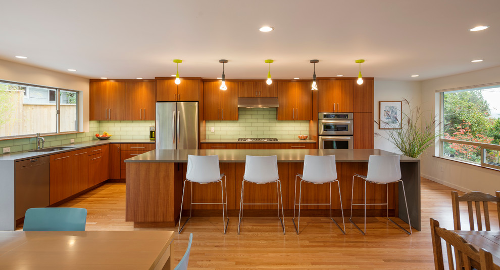 Moderne Wohnküche in L-Form mit flächenbündigen Schrankfronten, hellbraunen Holzschränken, Küchenrückwand in Grün und Küchengeräten aus Edelstahl in Seattle